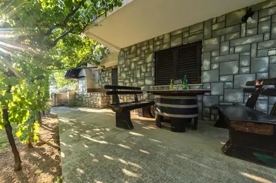 a patio with two picnic tables and a stone wall at Cottage near river Kolpa, vineyards,top location. in Adlešiči