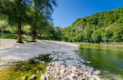 a river with rocks and a tree on the shore at Cottage near river Kolpa, vineyards,top location. in Adlešiči
