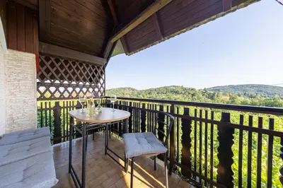 a patio with a table and chairs on a balcony at Cottage near river Kolpa, vineyards,top location. in Adlešiči