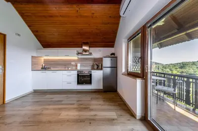 a kitchen with white cabinets and a large window at Cottage near river Kolpa, vineyards,top location. in Adlešiči