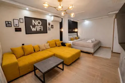 a living room with a yellow couch and a bed at Keleia Nova Vas Design Apartment Celje in Celje