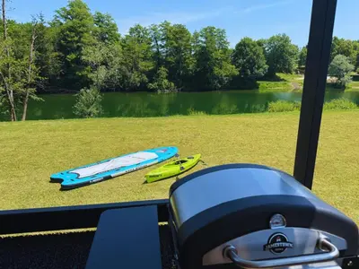 a kayak sitting on the grass next to a lake at Glamping Lucky House in Gradac