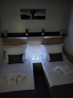 two beds in a room with white sheets and pillows at Glamping Lucky House in Gradac