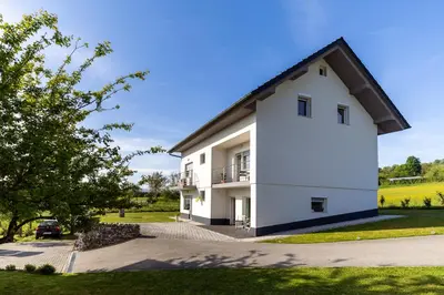 a white house with a black roof at Apartment Dalija - Cosy Apartment & Rooms with Massage Studio in Podčetrtek
