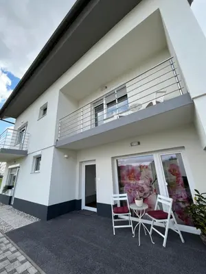 two chairs and a table in front of a house at Apartment Dalija - Cosy Apartment & Rooms with Massage Studio in Podčetrtek