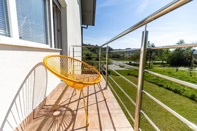 a yellow chair sitting on a balcony with a view at Apartment Dalija - Cosy Apartment & Rooms with Massage Studio in Podčetrtek