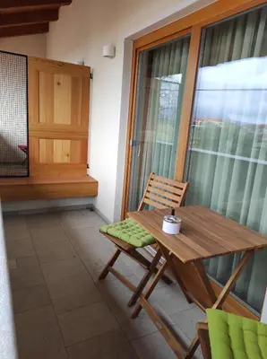 a wooden table and a chair on a balcony at Ferjančič estate rooms in Ajdovščina