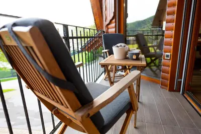 a wooden rocking chair on a balcony with a table at House 