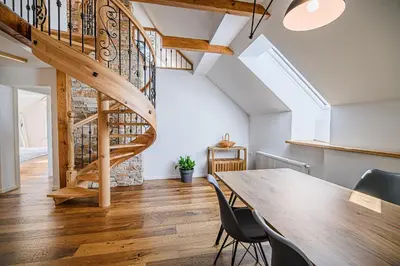 a dining room with a wooden table and a staircase at Mountain View Apartment with Sauna in Cerklje na Gorenjskem