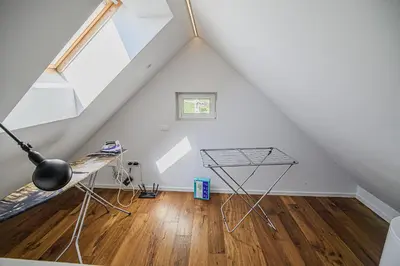a room with a table and a desk in the attic at Mountain View Apartment with Sauna in Cerklje na Gorenjskem