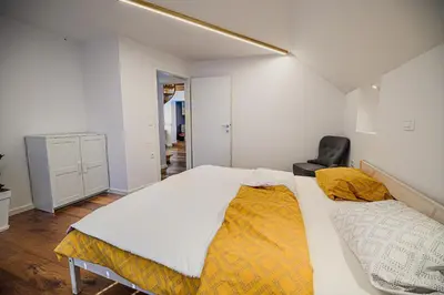a bedroom with a large bed and a black chair at Mountain View Apartment with Sauna in Cerklje na Gorenjskem
