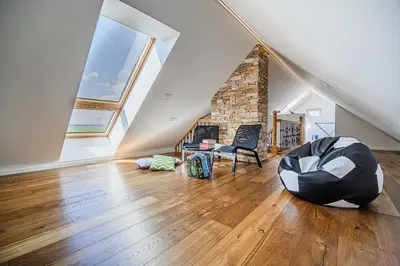 a living room with a couch and a chair in the attic at Mountain View Apartment with Sauna in Cerklje na Gorenjskem