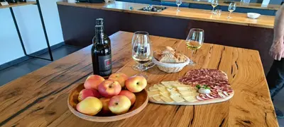 a wooden table with a bottle of wine and a bowl of fruit at WINERY AND APARTMENTS MAROF in Bistrica ob Sotli