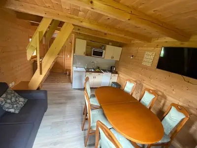 a dining room with a table and chairs and a kitchen at Brunarica Jeršin in Cerkno