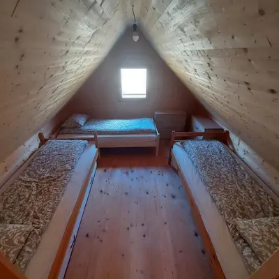 three beds in a wooden room with a window at Brunarica Jeršin in Cerkno