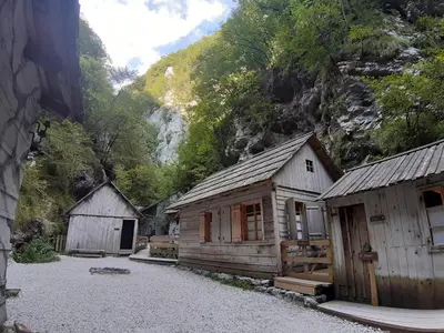a group of wooden buildings on a gravel road at Brunarica Jeršin in Cerkno