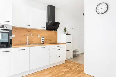 a kitchen with white cabinets and a clock on the wall at LA Studio in Maribor