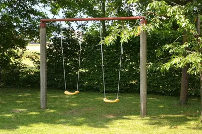 two swings in a park with trees and grass at Metkina Hiška -samooskrbna in Topovlje