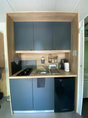 a small kitchen with blue cabinets and a sink at Metkina Hiška -samooskrbna in Topovlje