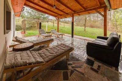 a screened in porch with a couch and chairs at Goričko Relax House in Kuzma