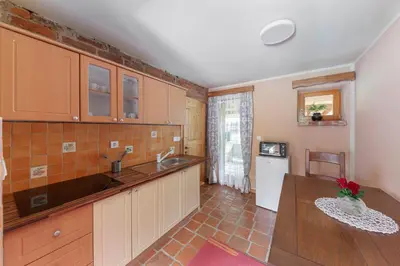 a kitchen with wooden cabinets and a table and a sink at Goričko Relax House in Kuzma