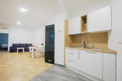 a kitchen with white cabinets and a living room at Apartment Center - Kersnikova in Ljubljana