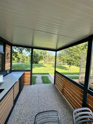 a screened porch with chairs and a view of a park at BB HOUSE KOLPA RIVERSIDE in Metlika