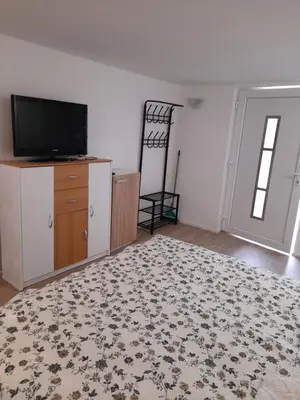 an empty living room with a television and a dresser at Studio Eržen in Zgornje Gorje