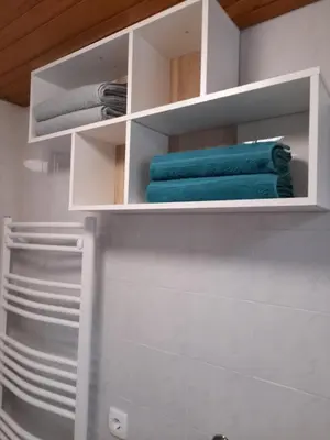 a bathroom with white shelves and blue towels at Studio Eržen in Zgornje Gorje