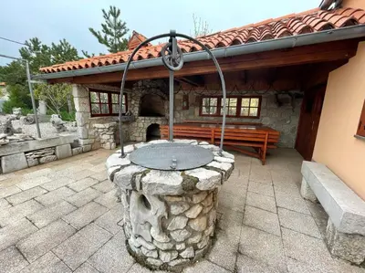 a stone patio with a stone fountain in front of a building at Hiša Pod Slavnikom in Podgorje
