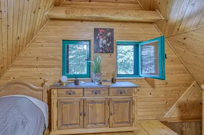 a bedroom in a log cabin with a bed and two windows at Fani's Riverside Cottage - Happy Rentals in Kostel