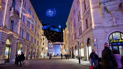 a group of people walking down a street at night at i Design 9 in Ljubljana