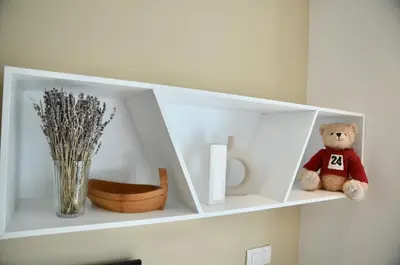 a white shelf with a teddy bear sitting on it at i Design 9 in Ljubljana