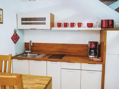 a kitchen with white cabinets and a wooden counter top at Petra Garden apartment in Bled