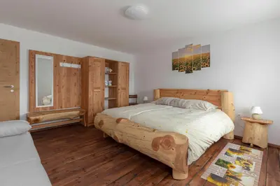 a bedroom with a large wooden bed and wooden floors at Počitniška Hiša Pr Martinovih in Postojna