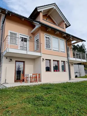 a house with a balcony and a table at Green Apartment Cerknica in Cerknica