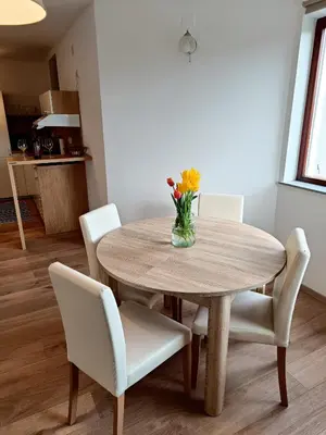 a dining room table with white chairs and a vase of flowers at Green Apartment Cerknica in Cerknica