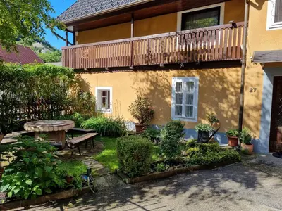 a garden in front of a house with a table and a balcony at Blacksmith in Kropa