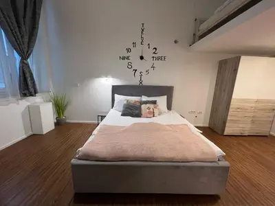 a bedroom with a bed and a clock on the wall at Absolutum Apartments in Ljubljana