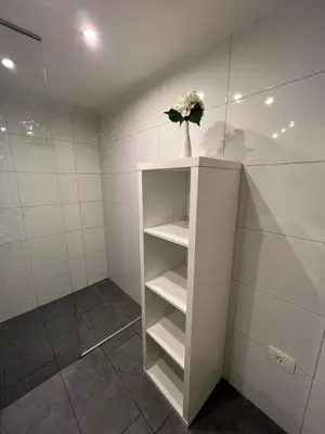 a bathroom with a white shelf with a vase of flowers at Absolutum Apartments in Ljubljana