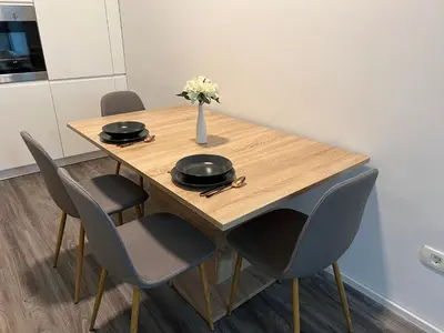 a wooden table with chairs and a vase of flowers on it at Absolutum Apartments in Ljubljana