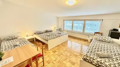a living room with two beds and a table and a room with a tableablish at Center Station ROOMS in Ljubljana