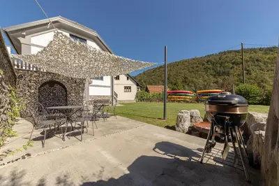 a grill in a backyard with a table and chairs at DoLodge Homestead & Camper Parking Kolpa River Canyon in Stari Trg ob Kolpi