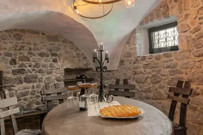 a dining room with a table and a stone wall at DoLodge Homestead & Camper Parking Kolpa River Canyon in Stari Trg ob Kolpi