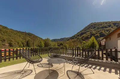 three chairs and a table on a patio with mountains at DoLodge Homestead & Camper Parking Kolpa River Canyon in Stari Trg ob Kolpi